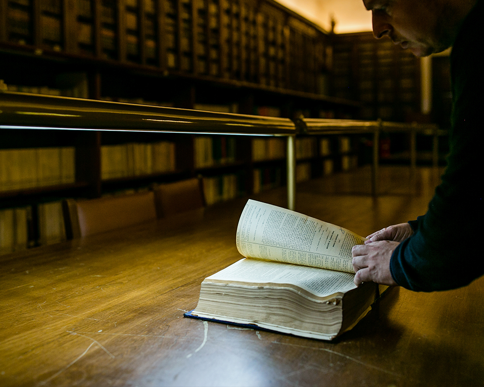 Persona leyendo un libro antiguo en la biblioteca del Hospital Real